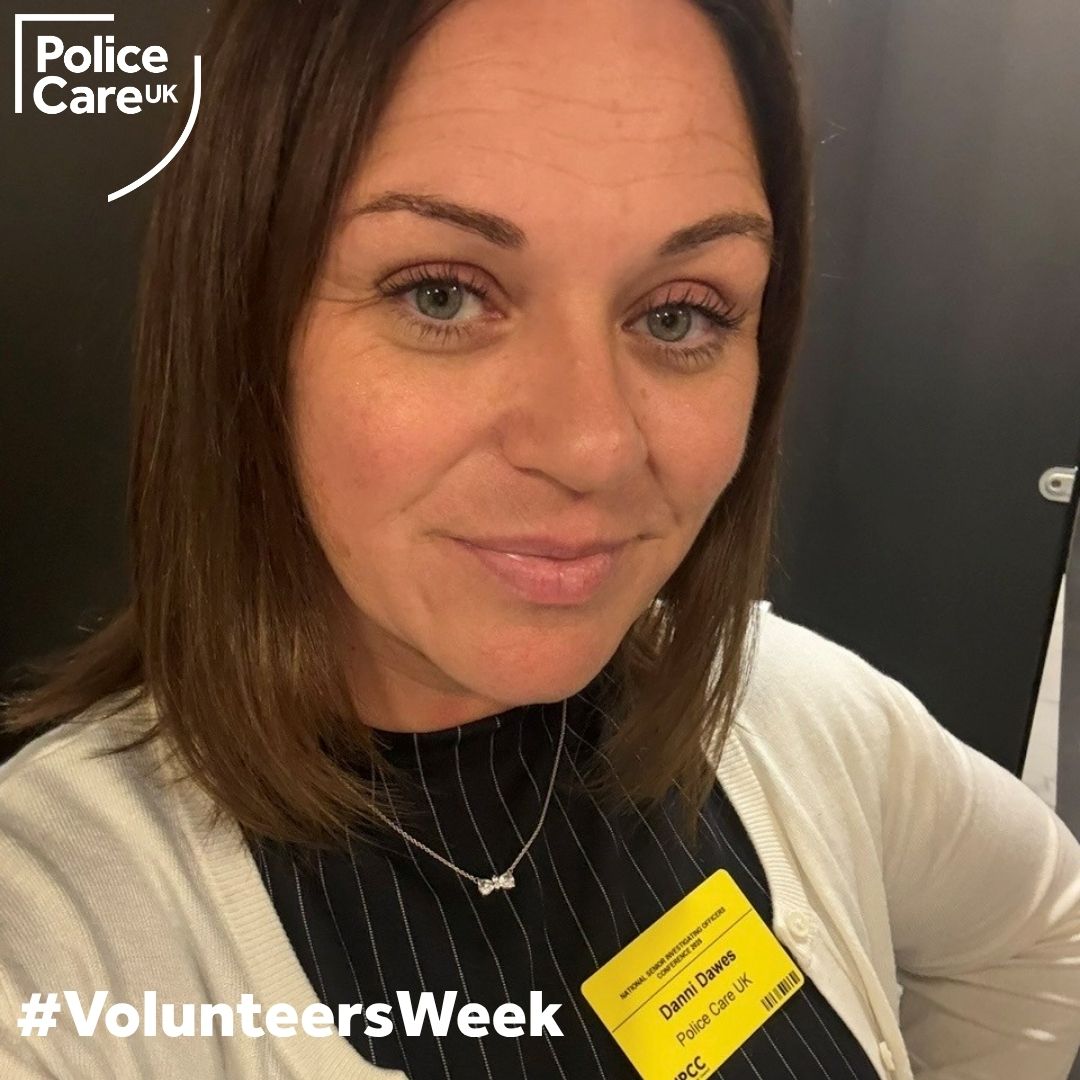 Image of dark haired Danni smiling for the camera while volunteering for Police Care UK