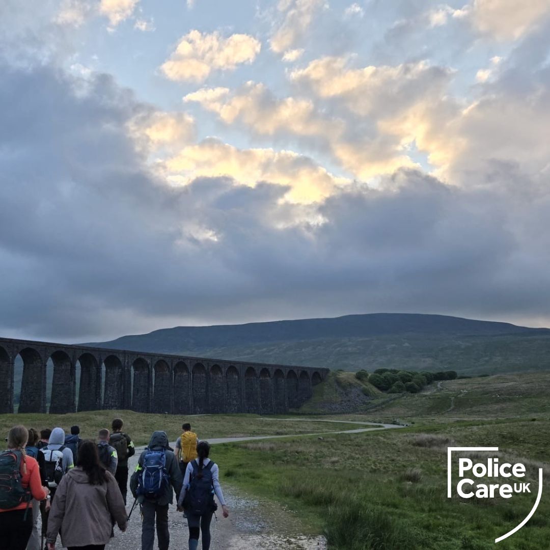 Landscape shot of Scafell Pike with an viaduct in the distance and a group of walkers in the foreground