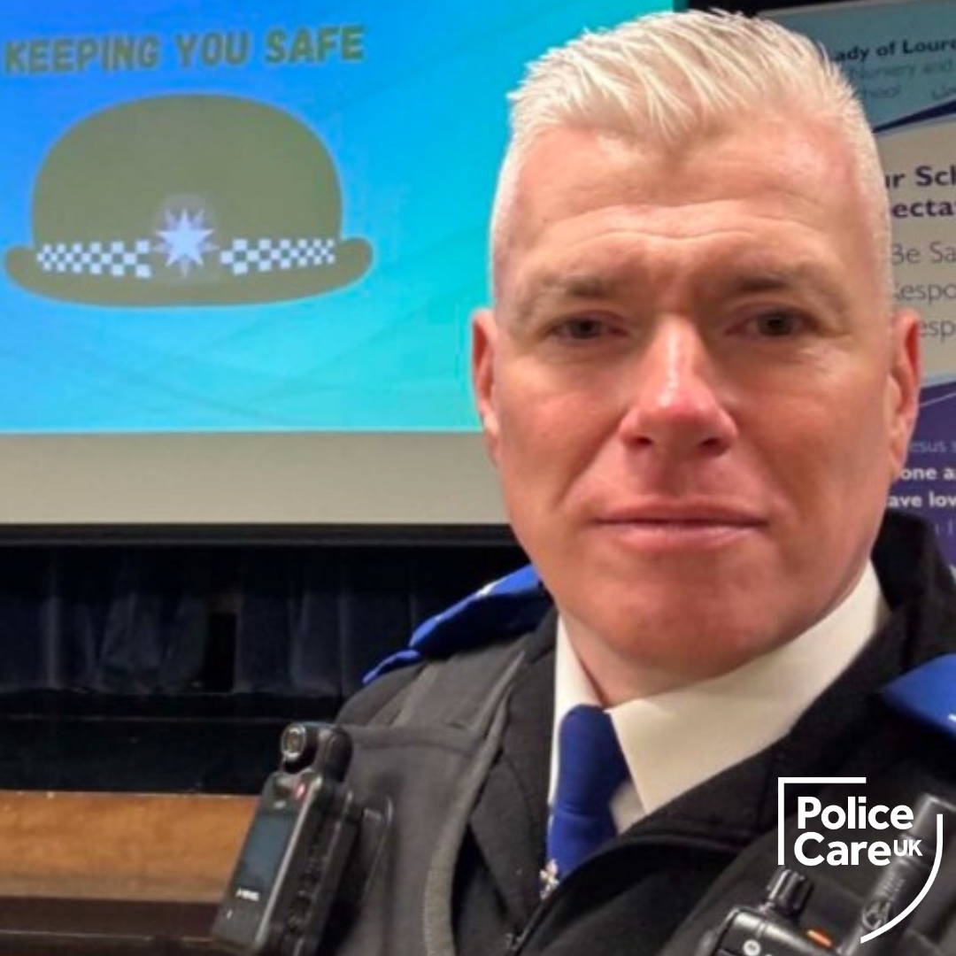 Portrait of Barry Calder in uniform and looking straight at the camera. Behind him is a big screen